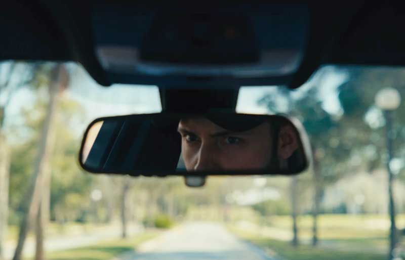 man looking into rear view mirror